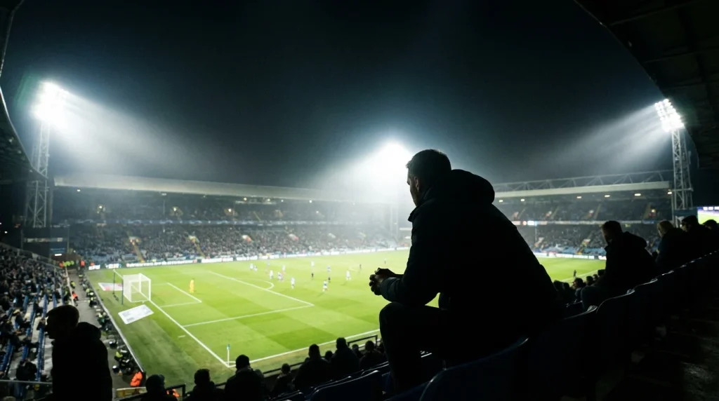 Tifoso concentrato guarda una partita di calcio in uno stadio illuminato di sera
